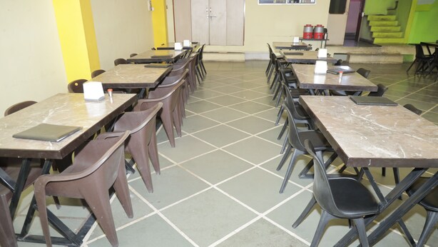 A cafeteria with multiple tables and chairs arranged in rows.