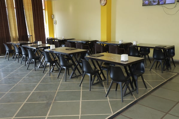 Un comedor con mesas y sillas dispuestas para sentarse.