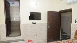 A hotel room with a bed, a TV mounted on the wall, a door, and a staircase.