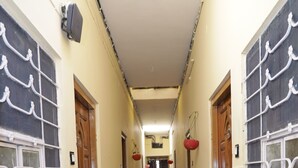 A corridor with tiled flooring, potted plants, and doors on either side.