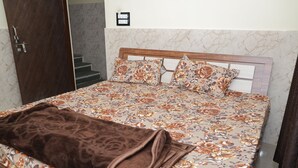 A bed with a floral bedspread, a brown blanket, and a wooden headboard.