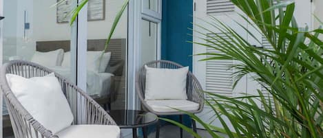 A glass-enclosed outdoor seating area with wicker chairs and a table.