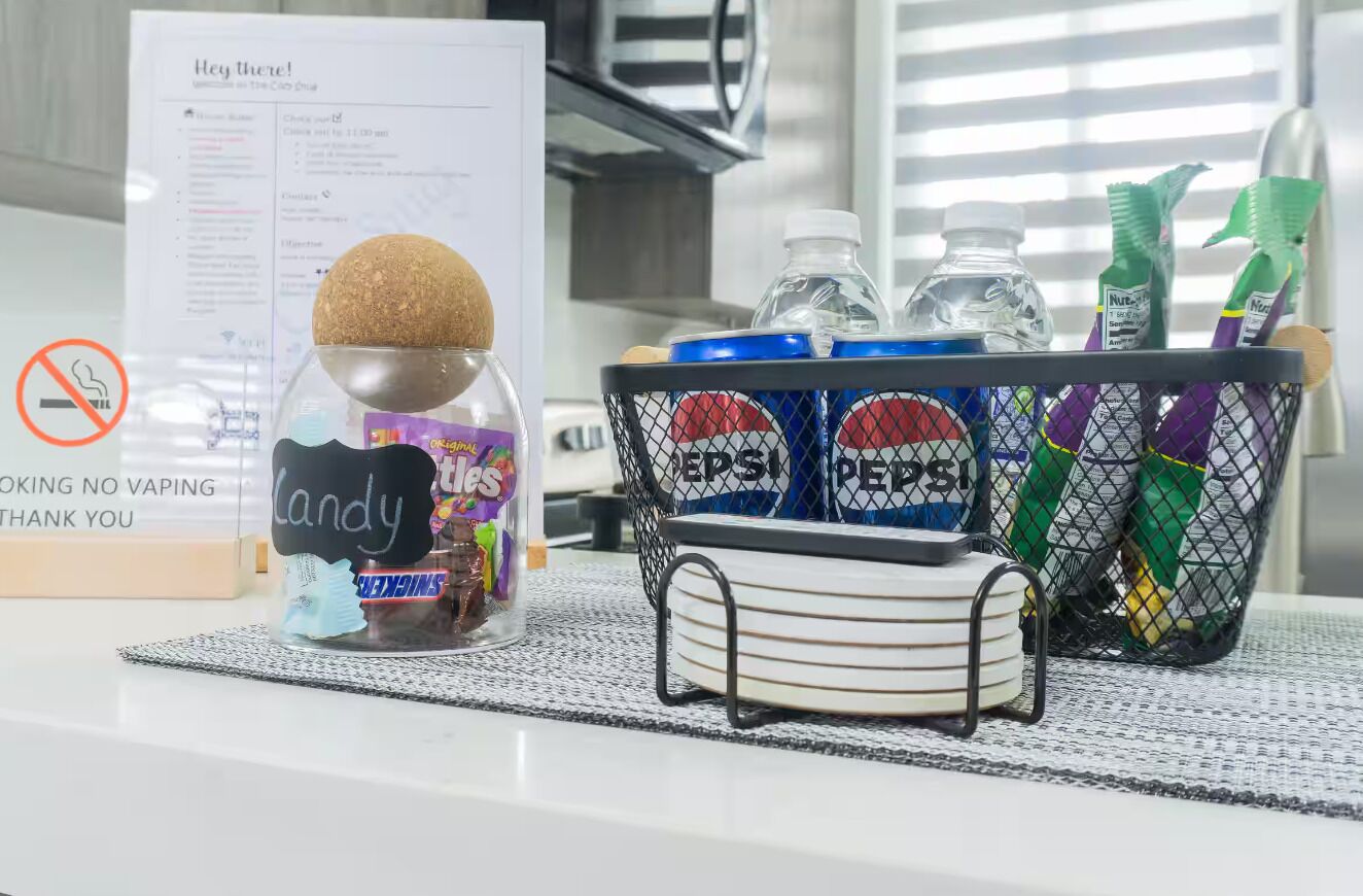 A hotel room with a snack basket containing candy, water bottles, and toiletries.