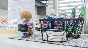 A hotel room with a snack basket containing candy, water bottles, and toiletries.