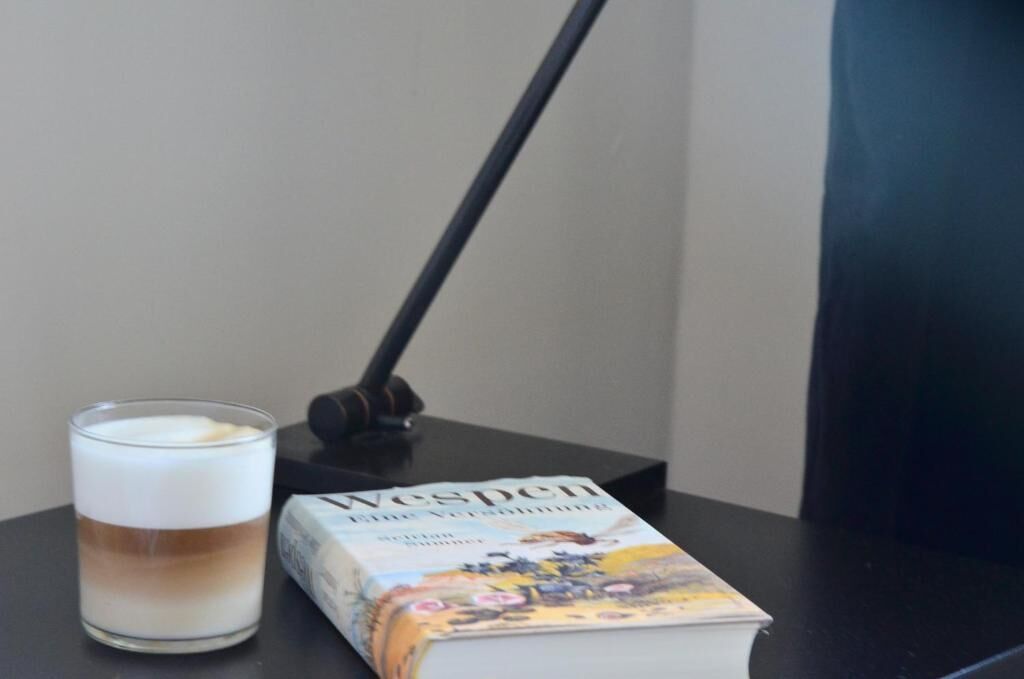 Un libro titulado 'Wespen' junto a una taza de café sobre una mesa.