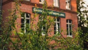 A red brick building with multiple windows and a green sign. - An den Wiesen. Gasthaus am Finowkanal (Wandlitz)