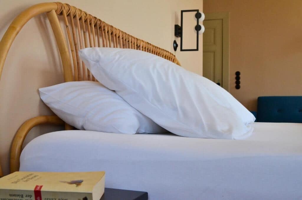 Una cama con ropa de cama blanca y cabecera de madera.