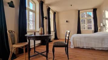 A room with a bed, a table with chairs, and a window with curtains.