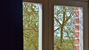 A window with a view of a tree and a brick wall. - An den Wiesen. Gasthaus am Finowkanal (Wandlitz)