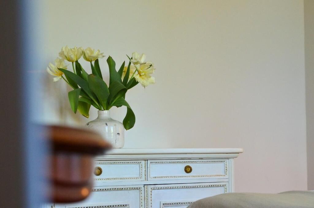 Une commode blanche avec un vase de fleurs.