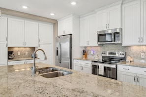 A modern kitchen with white cabinetry, stainless steel appliances, a granite countertop, and a built-in oven. - One Particular Harbour Lagoon View 391-203 · Pet-Friendly (Bradenton)
