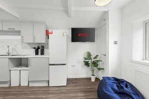 Una cocina moderna con armarios blancos, horno empotrado y microondas. Un televisor de pantalla plana sobre el horno muestra el logo de Netflix.