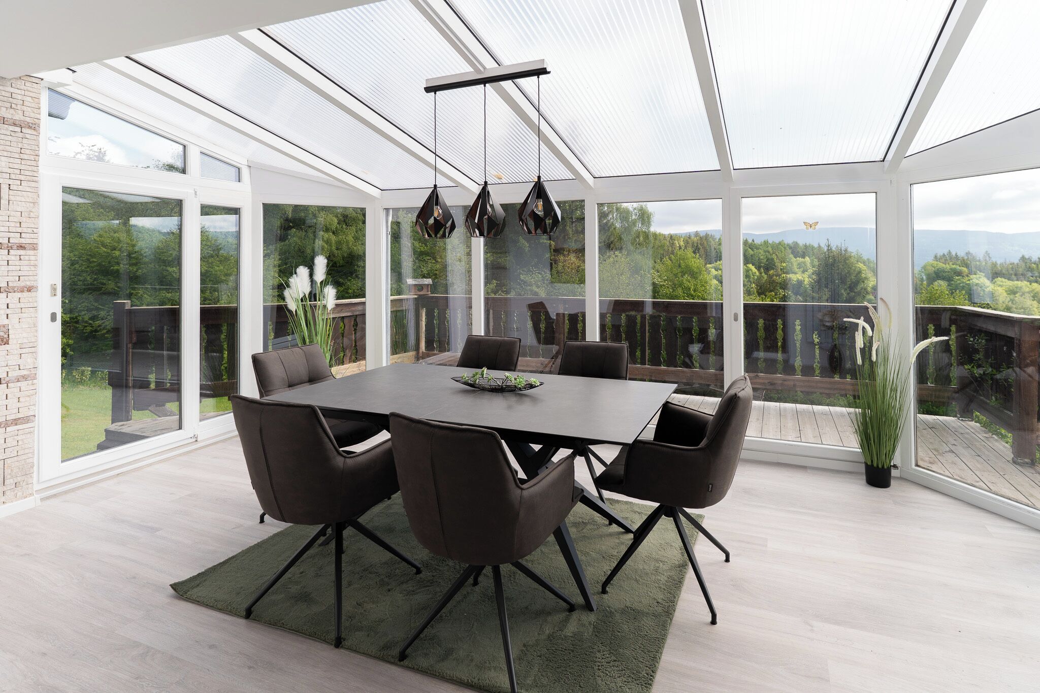 Ein moderner Essbereich mit einer verglasten Terrasse, einem großen Tisch und Stühlen.