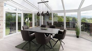 Ein moderner Essbereich mit einer verglasten Terrasse, einem großen Tisch und Stühlen.