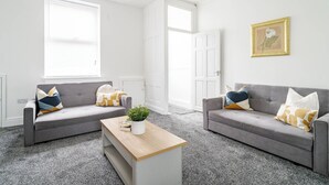 Un salón moderno con dos sofás grises, una mesa de centro de madera y una planta en maceta.