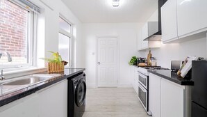 Una cocina compacta con lavadora, un lavamanos y una estufa.