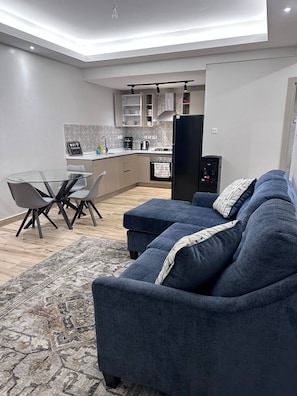 Un espace de vie moderne comprenant un canapé, une table à manger et une cuisine en arrière-plan.