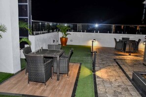 Ein möblierter Patio mit Tisch, Stühlen, einer Topfpflanze und einer Steinmauer.