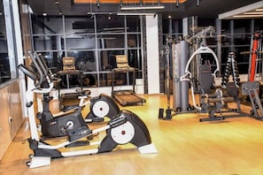 Une salle de sport équipée de divers appareils d’exercice, notamment des tapis de course, des appareils de musculation et des poids libres.