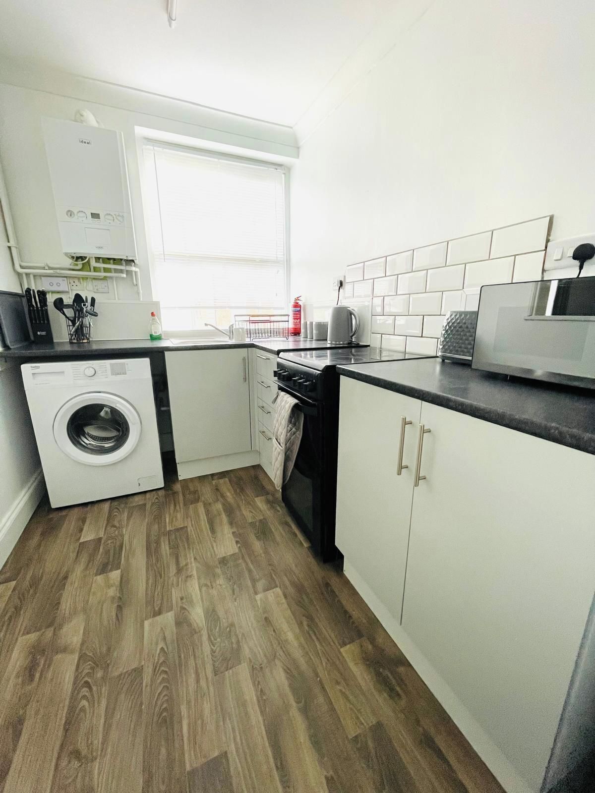A compact kitchen with a washing machine, a stove, and a microwave.