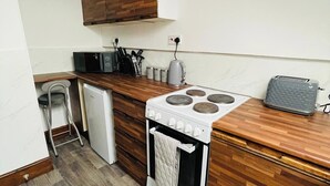 Una cocina compacta con estufa blanca, armarios de madera y una pequeña encimera.