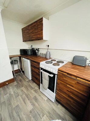 Una cocina compacta con estufa blanca, armarios de madera y una pequeña encimera.