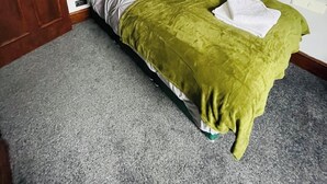 Un dormitorio con cama, una puerta y una lámpara fijada a la pared.