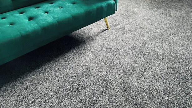 Una habitación con un sofá verde, una mesa de comedor con sillas y un techo inclinado.