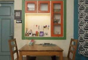 Una habitación con una mesa de madera, dos sillas, un aparador con puertas de cristal y una pared con diseño.