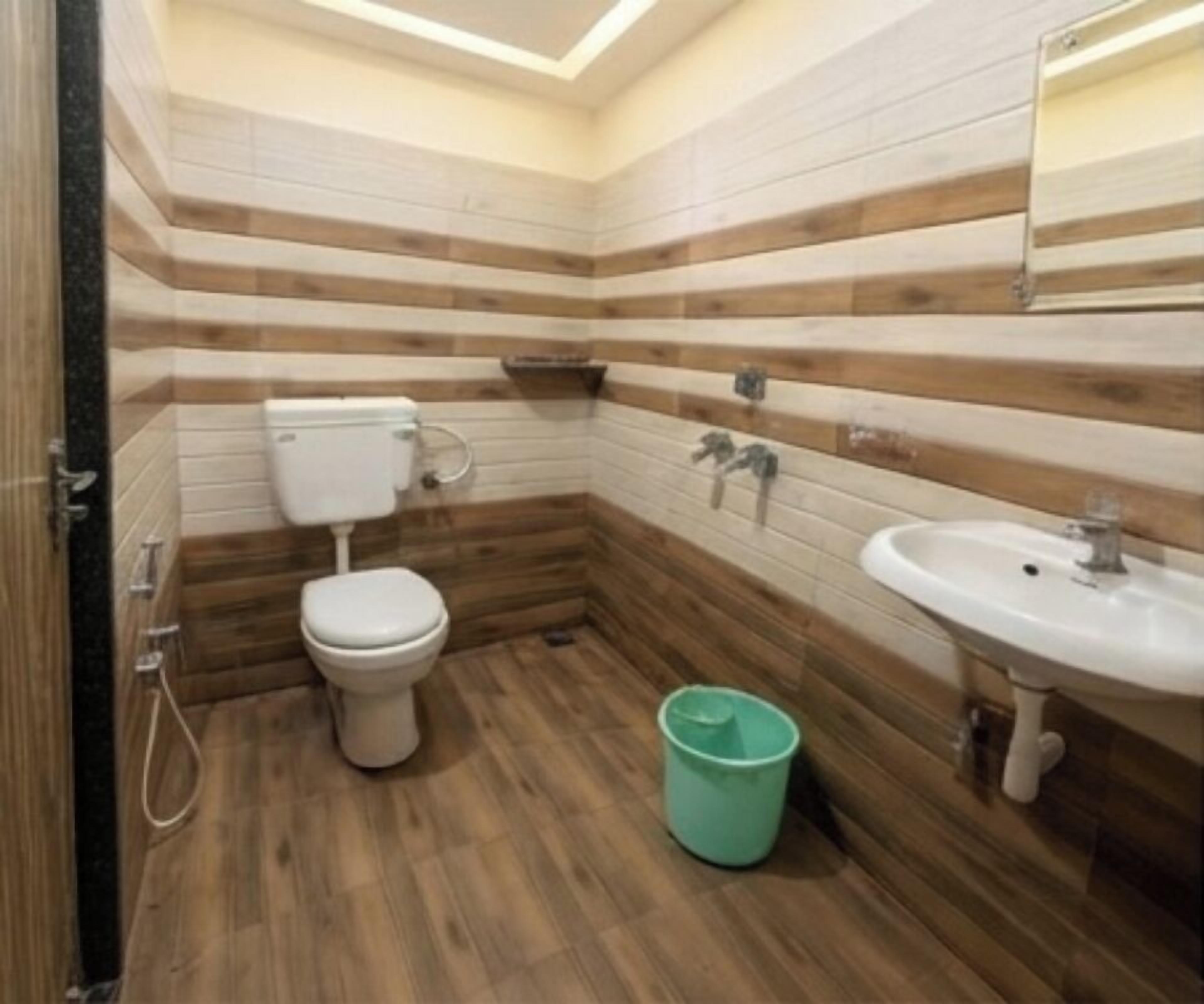 Baño con inodoro, lavamanos y paneles de madera.