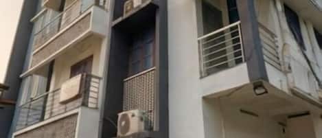 A multi-story building with balconies, air conditioning units, and a flat roof.