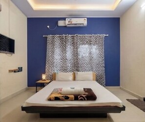 A modern bedroom with a bed, air conditioning unit, and patterned curtains. - Hotel Bright stays (Thiruvananthapuram)