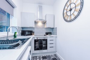 A compact kitchen with a built-in oven, a microwave, and a sink. - Spacious Home with Free Parking | Atherton House (Greater Manchester)