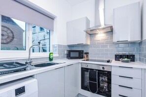 Une cuisine moderne équipée d’un lave-vaisselle, d’un four, d’un four à micro-ondes et d’une fenêtre donnant sur la rue.