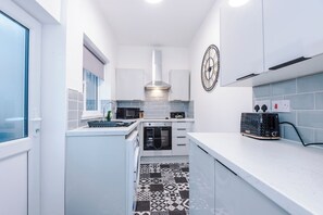 A compact kitchen with white cabinetry, a microwave, a toaster, and a patterned floor. - Spacious Home with Free Parking | Atherton House (Greater Manchester)