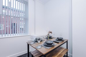 A dining area with a table set for four, including plates, bowls, glasses, and cutlery. - Spacious Home with Free Parking | Atherton House (Greater Manchester)