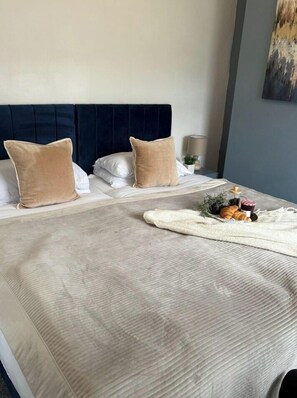 A neatly made bed with a dark headboard, two beige pillows, and a white blanket. - Spacious Stay by the Docks | Your Wallasey Getaway (Liverpool / Merseyside)