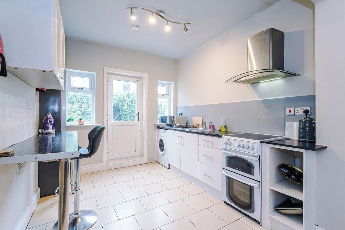 A modern kitchen with a washing machine, oven, and built-in microwave.