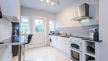 A modern kitchen with a washing machine, oven, and built-in microwave.