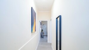 A narrow hallway with a wooden floor, white walls, and a door at the end. - Rishton Stay | Shops & Transport | Near Blackburn (Lancashire)