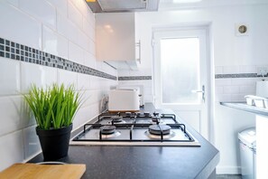 Une cuisine moderne avec une cuisinière à gaz, des carreaux blancs et une plante en pot.
