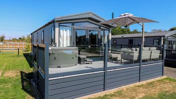 Ein moderner Außenbereich mit Whirlpool, Glasumrandung, Sitzgelegenheiten und Sonnenschirm.