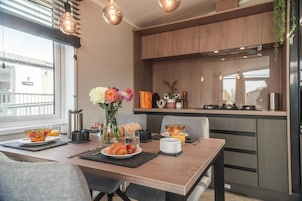 Una cocina moderna con armarios de madera, una mesa de comedor con alimentos para el desayuno y vistas de la ciudad.