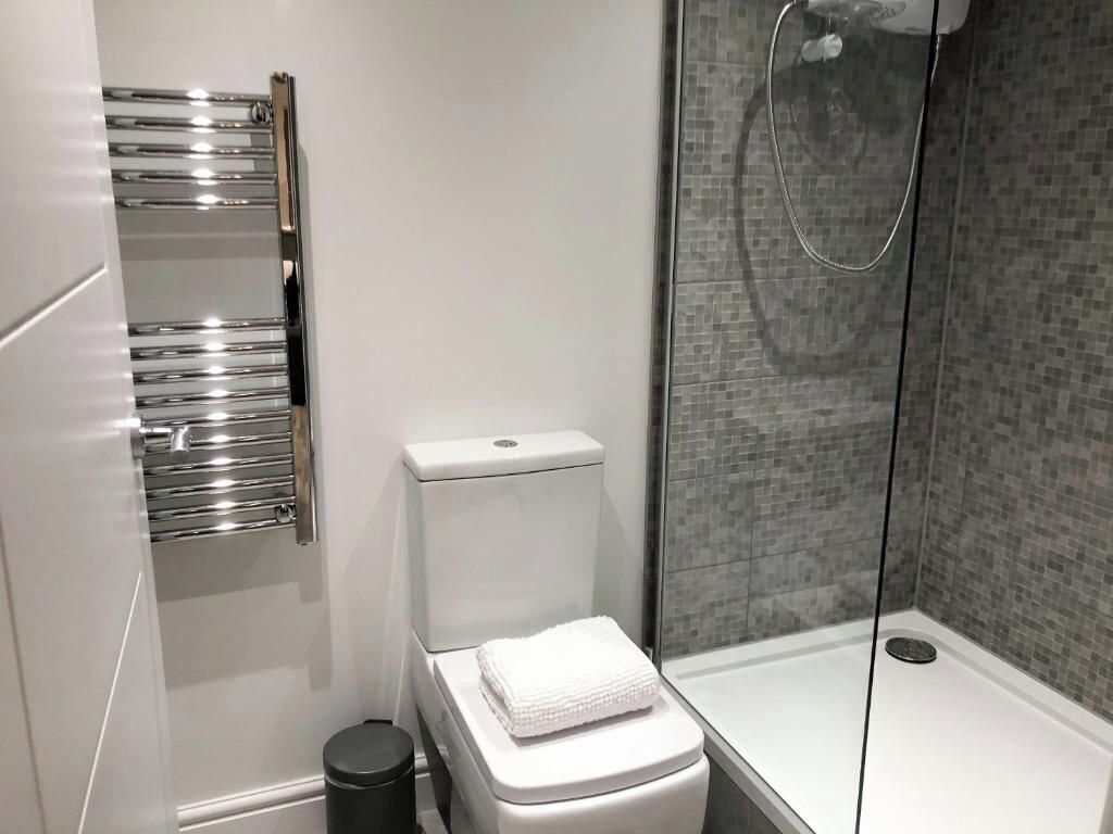 A modern bathroom with a toilet, a shower, and a towel rack.