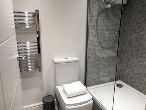 A modern bathroom with a toilet, a chrome towel rack, and a shower area. - Manchester Base | Heaton Park & Shops | Parking (Harpurhey)
