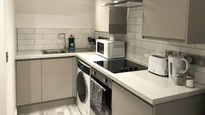 Eine kleine Küche mit Geschirrspüler, Mikrowelle, Toaster und Wasserkocher.