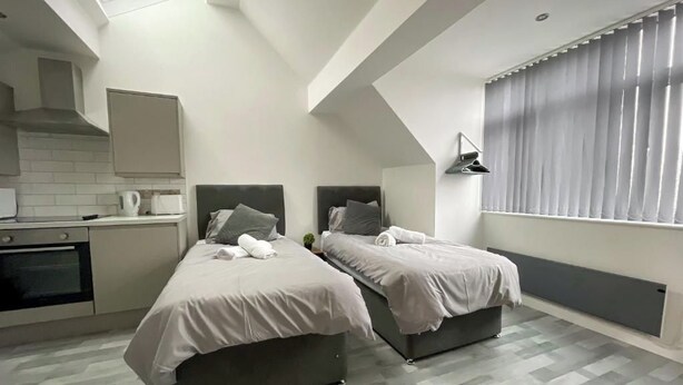 Ein modernes Schlafzimmer mit zwei Betten, einer Küchenzeile und einem Oberlicht.