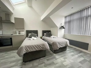 Ein modernes Schlafzimmer mit zwei Betten, einer Küchenzeile und einem Oberlicht.