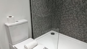 Ein modernes Badezimmer mit Toilette, einer Toilettenrolle und einer Badewanne.