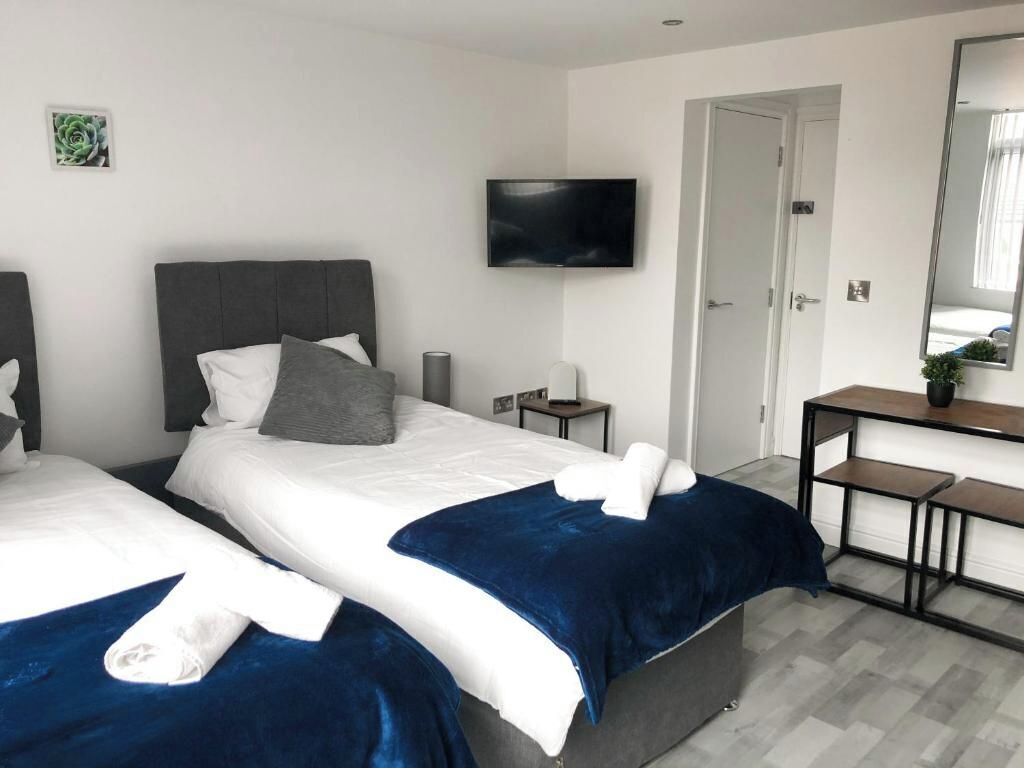 A hotel room with two beds, a TV, a desk, and a mirror.